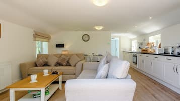 A living room with a sofa, a coffee table, and a kitchen area with cabinets and appliances.