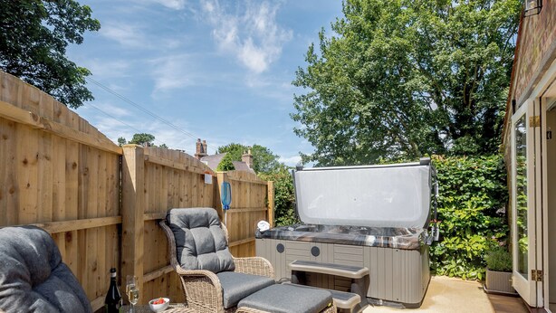 Une terrasse dotée de meubles en osier, d’un barbecue et d’une clôture en bois.