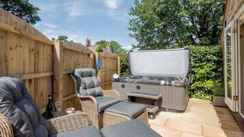 Een terras met rieten meubilair, een barbecue en een houten omheining.