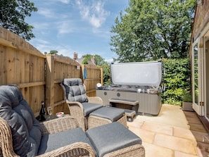 Eine Terrasse mit Korbmöbeln, einem Grill und einem Holzzaun.