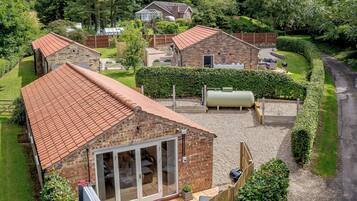 Een wooneiland met een huis van baksteen, een tuinkamer, een barbecueplaats en een grote waterreservoir.