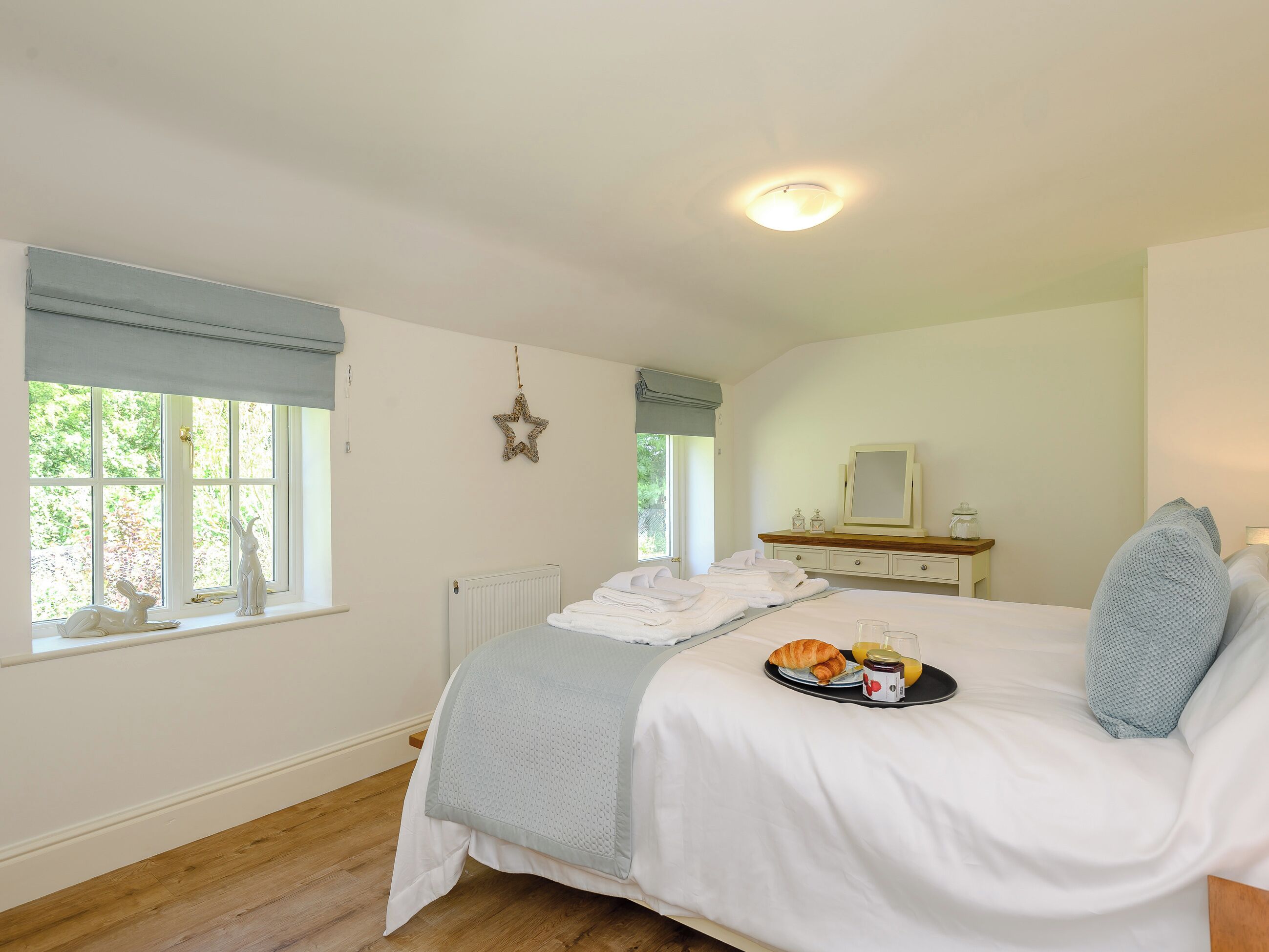 Ein Schlafzimmer mit Bett, Schminktisch, einem Fenster mit Aussicht und einer Stern-Dekoration an der Wand.