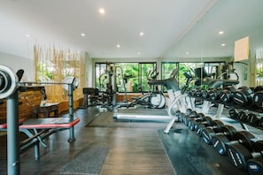 Un gimnasio moderno con máquinas de cardio, equipo de levantamiento de pesas y mancuernas.
