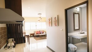 Un baño moderno con un espejo grande, un inodoro y un lavamanos. Hay un pasillo que conduce a una sala de estar con un sofá y una mesa de centro.