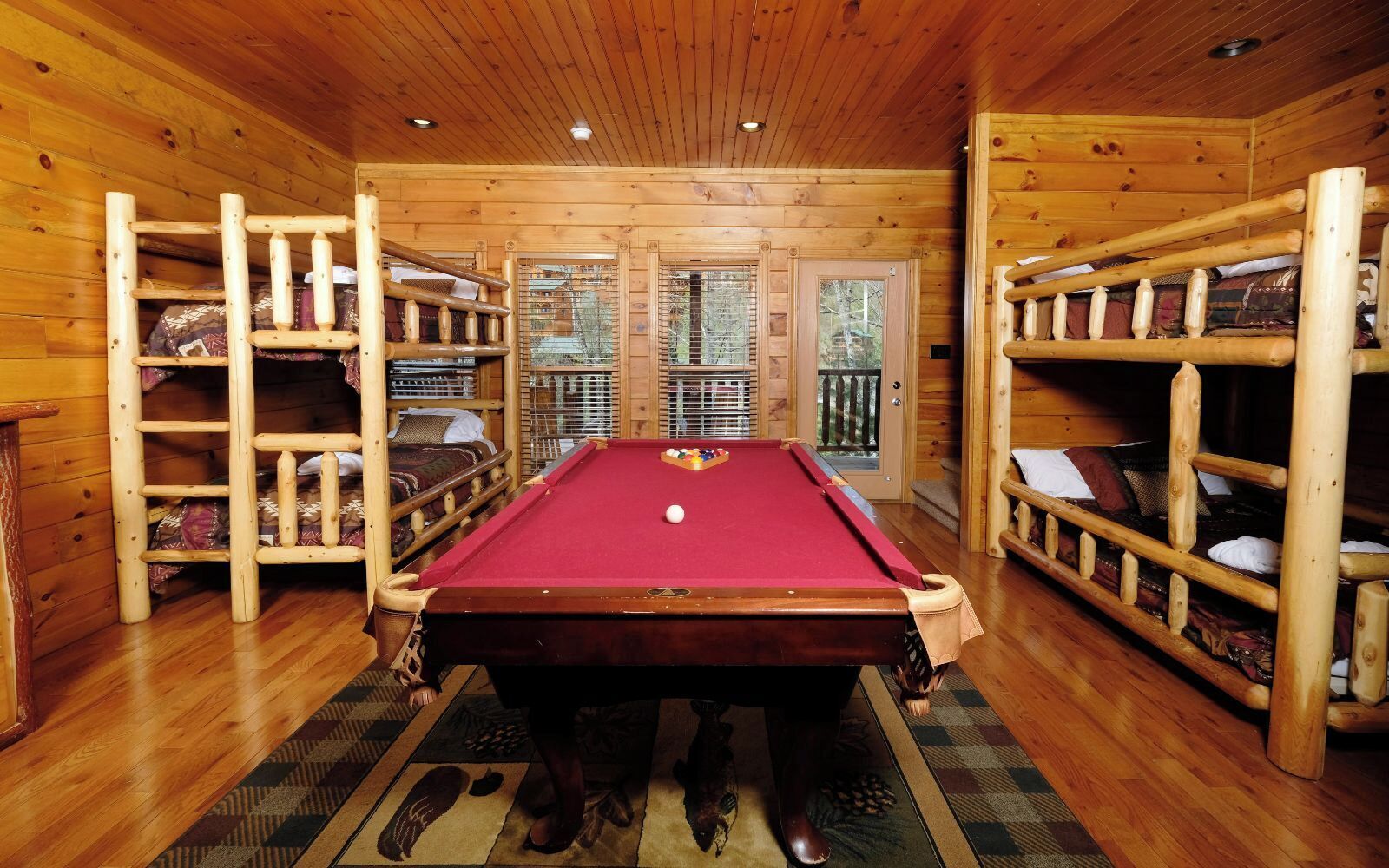 A pool table in a wooden cabin with built-in shelving on either side.