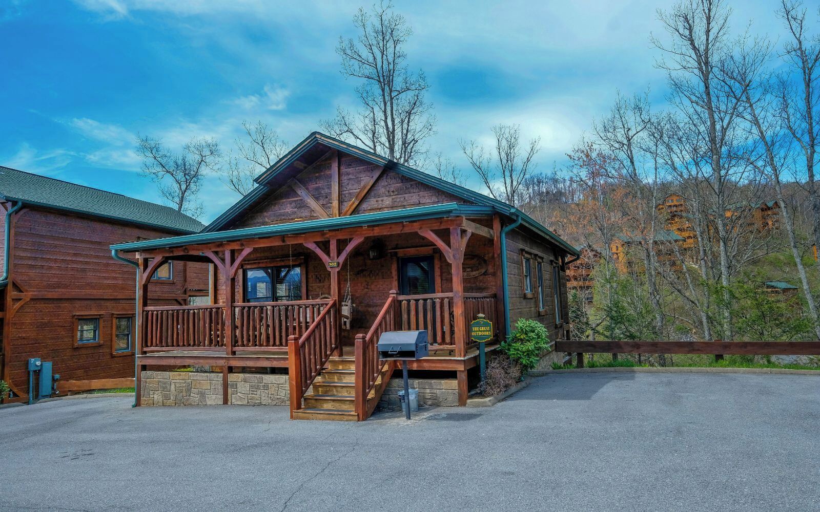 A wooden lodge with a porch, a staircase, and a sign indicating it's a great outdoors destination.