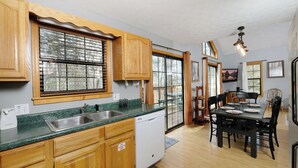 A kitchen with wooden cabinets, a dishwasher, and a dining area with a table and chairs.
