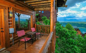 Une cabane en bois dotée d’un balcon, d’une table avec des chaises, et offrant une vue sur un lac et des montagnes.