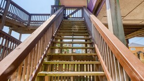 A wooden staircase with a handrail leading to a green and purple building. - Seas The Moment before it passes you by. (Freeport)