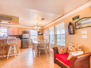 A kitchen with wooden cabinets, a dining table with chairs, a refrigerator, and a chandelier. - ‘Seas The Moment’….. before it passes you by. (Freeport)