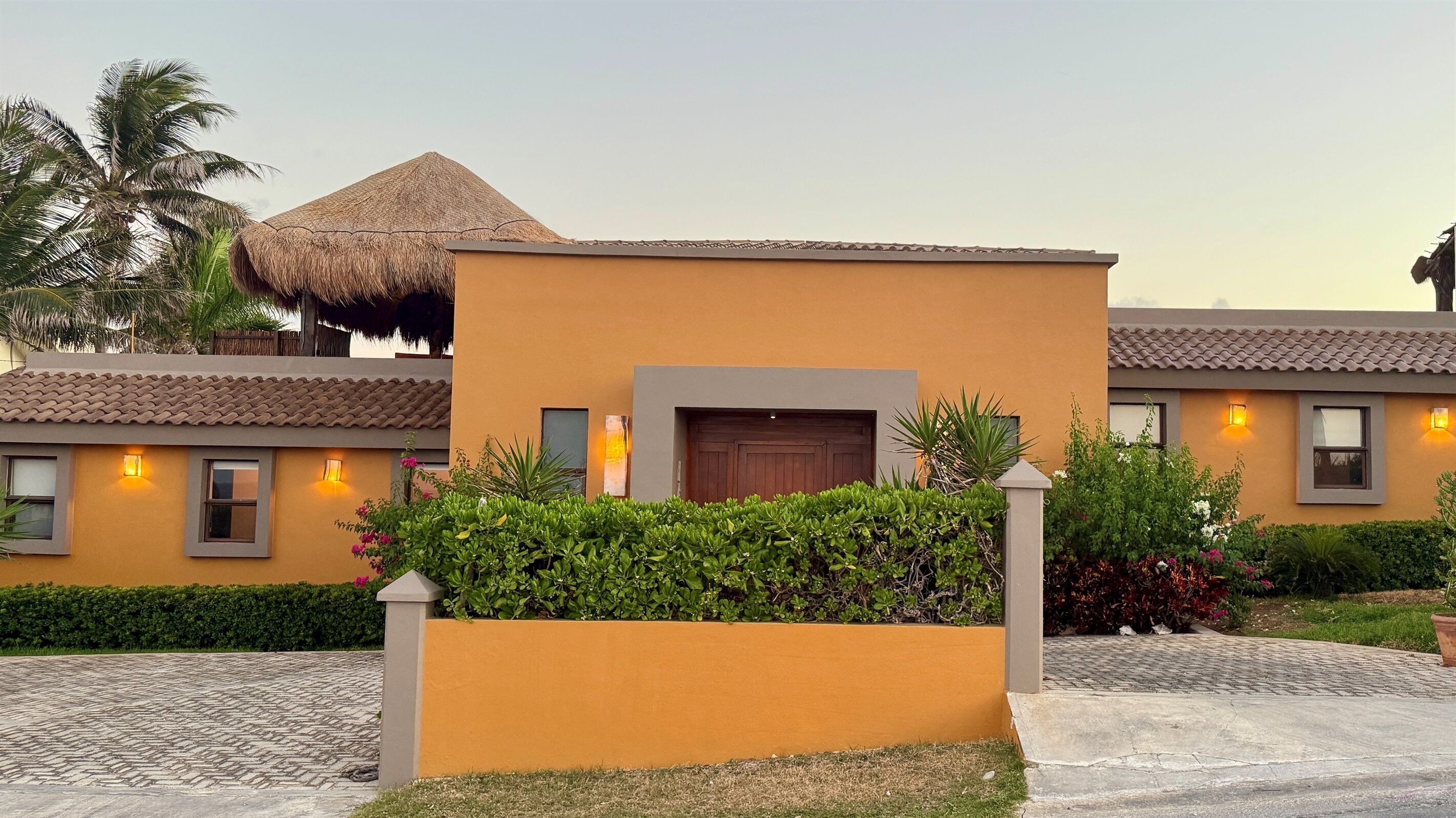 A modern building with a thatched roof, a well-maintained garden, and a paved walkway.