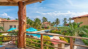 A pool area with a wooden railing, palm trees, and a clear sky. - Luxury Villa In A Private Beachfront Oasis, W/ Tennis, Pickleball, Dock/ Pool! (San Pedro)