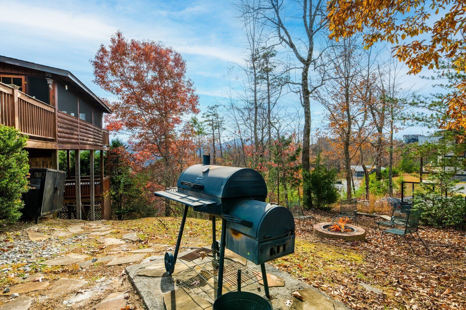 A backyard with a barbecue grill, a wooden deck, and a stone pathway.