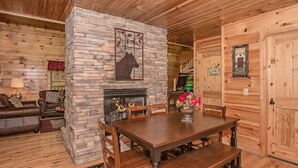 A cozy living room with a stone fireplace, wooden furniture, and a rustic interior. - 🐻Can't Bear to Leave: Theater, Two King Suites, Games, Fireplaces & Hot Tub🌄 (Pigeon Forge)