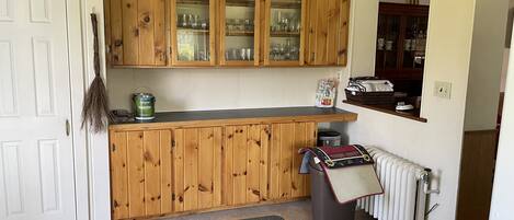 A kitchen with wooden cabinets, a black countertop, a radiator, and a trash bin.