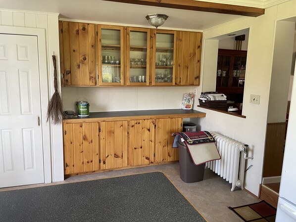 A kitchen with wooden cabinets, a black countertop, a radiator, and a trash bin.