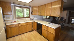Una cocina con armarios de madera, lavavajillas y un comedor con mesa y sillas.