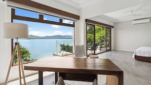 A bedroom with a large window offering a view of a lake and mountains. - 5-BD Beachfront, Ocean-View Hillside Home (Playa Flamingo)
