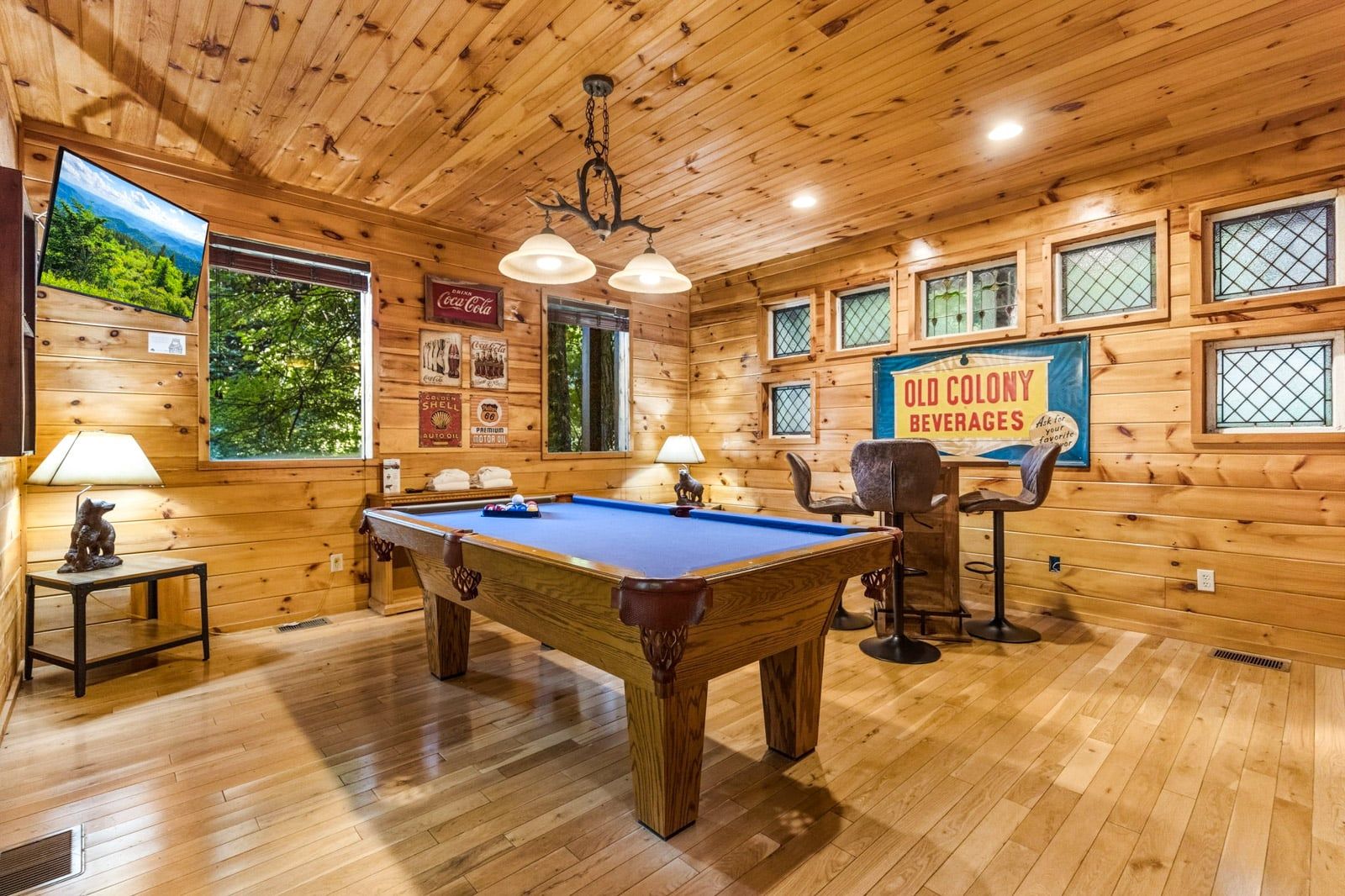 A wooden interior with a pool table, seating, and a Coca-Cola sign.