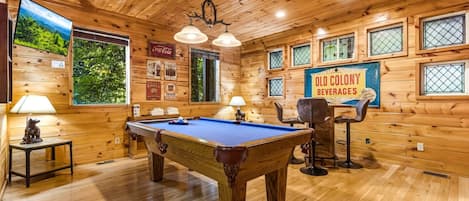 A wooden interior with a pool table, seating, and a Coca-Cola sign.