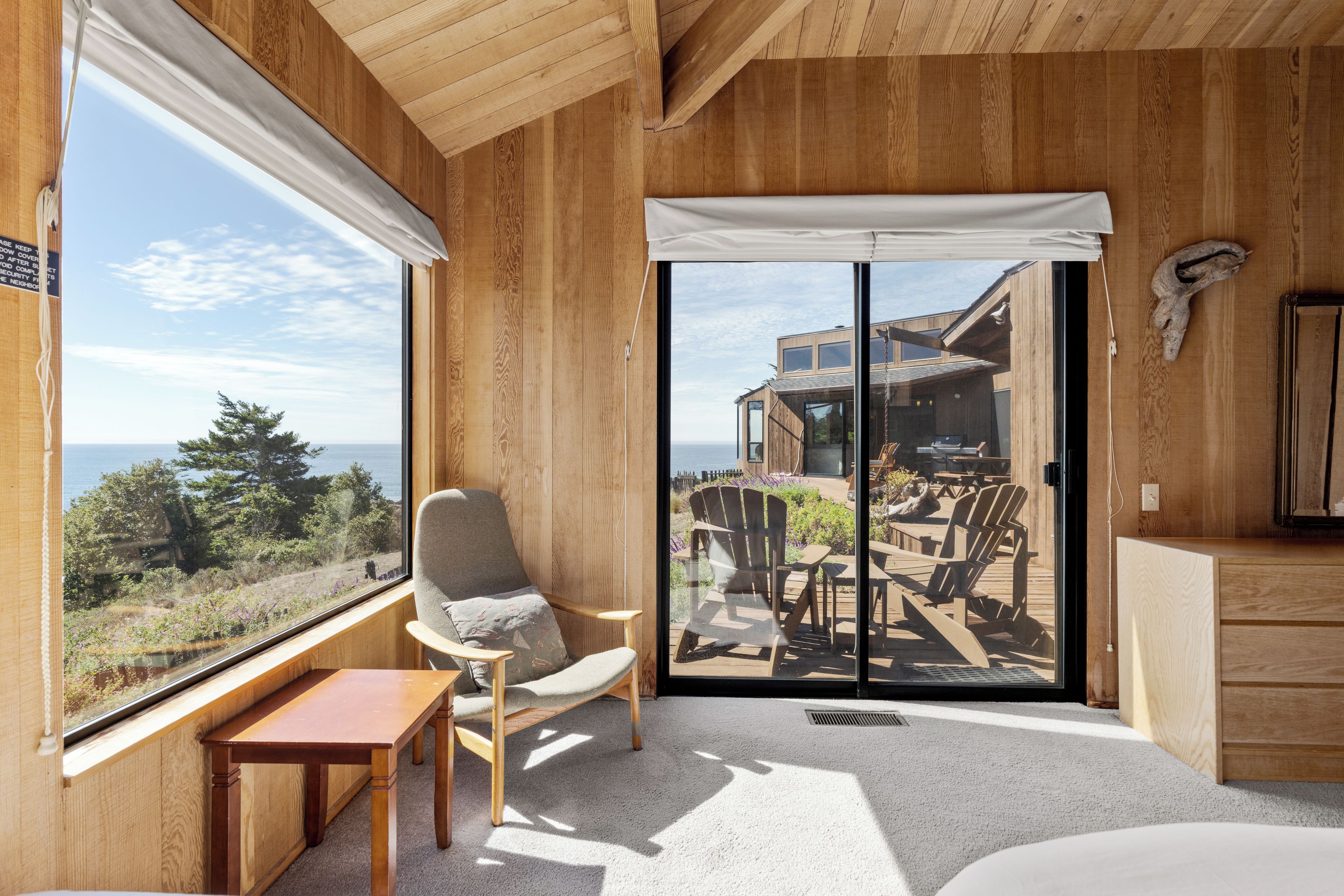 A room with a large sliding glass door leading to an outdoor deck with chairs and a table.