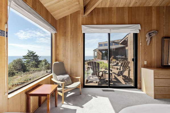 A room with a large sliding glass door leading to an outdoor deck with chairs and a table.