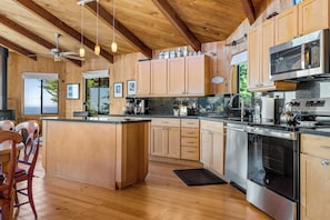 A modern kitchen with wooden cabinetry, stainless steel appliances, and a large island.