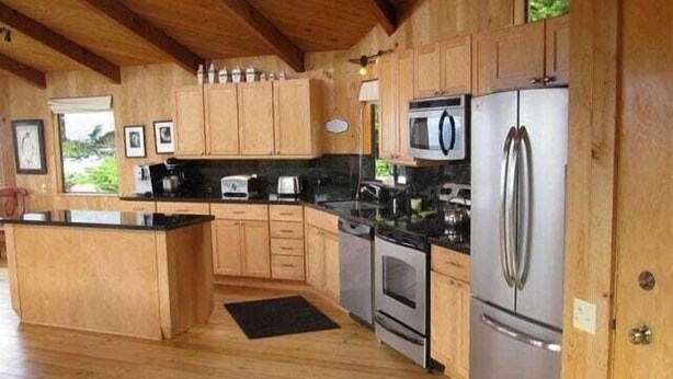 Una cocina con gabinetes de madera, un refrigerador, un microondas y una estufa.
