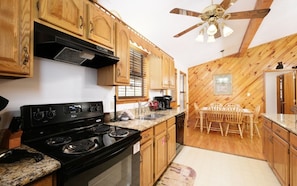 Kitchen with a wooden table and chairs, a refrigerator, and a black stove.