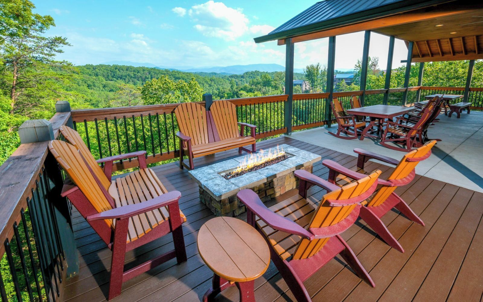 A deck with Adirondack chairs, a fire pit, and a covered area with tables and chairs.