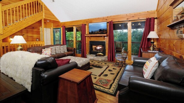 Interior acogedor de una cabaña con chimenea, paredes de madera y un espacio de estar confortable.