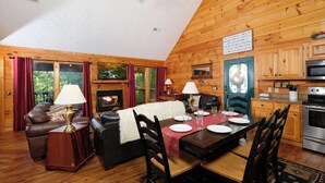 Interior acogedor de una cabaña con comedor, chimenea y paredes de madera.