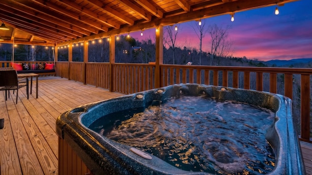 A wooden deck with a hot tub, a swing, and a table with chairs. - Mountain VIEWS! Hot Tub, Handicap Accessible - 15 mins to downtown Gatlinburg (Sevierville)