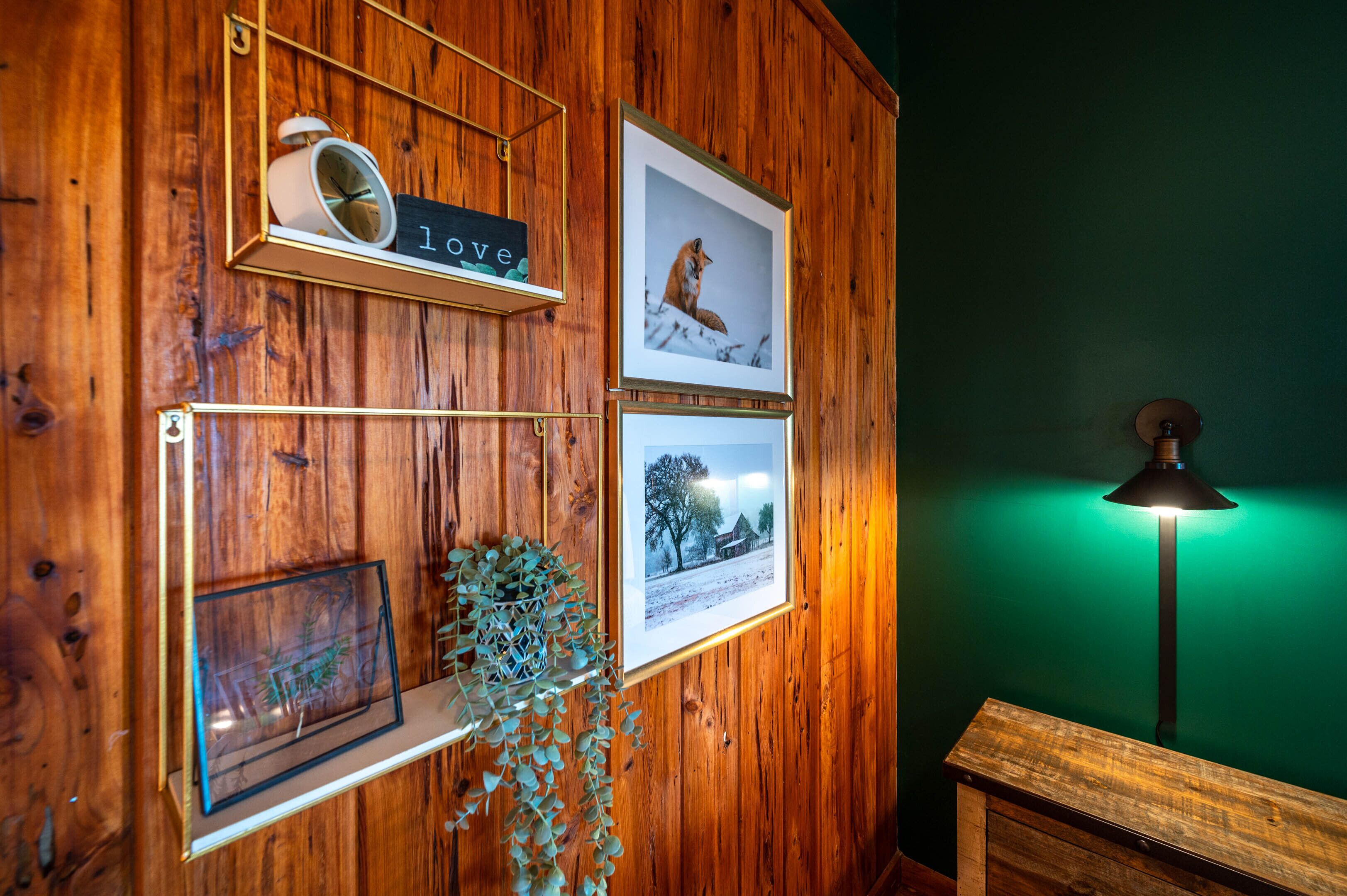 Pared de madera con cuadros enmarcados, un reloj y un letrero que dice 'love'.