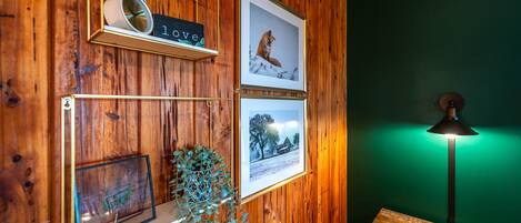 Pared de madera con cuadros enmarcados, un reloj y un letrero que dice 'love'.