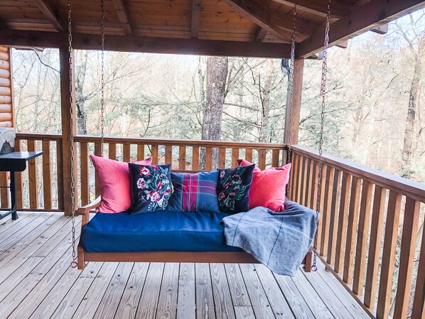 A wooden deck with a swing seat, a table, and a view of trees. - Leaf Peeping, VIEWS, Hot Tub, Handicap Accessible, 15mins to downtown Gatlinburg (Sevierville)