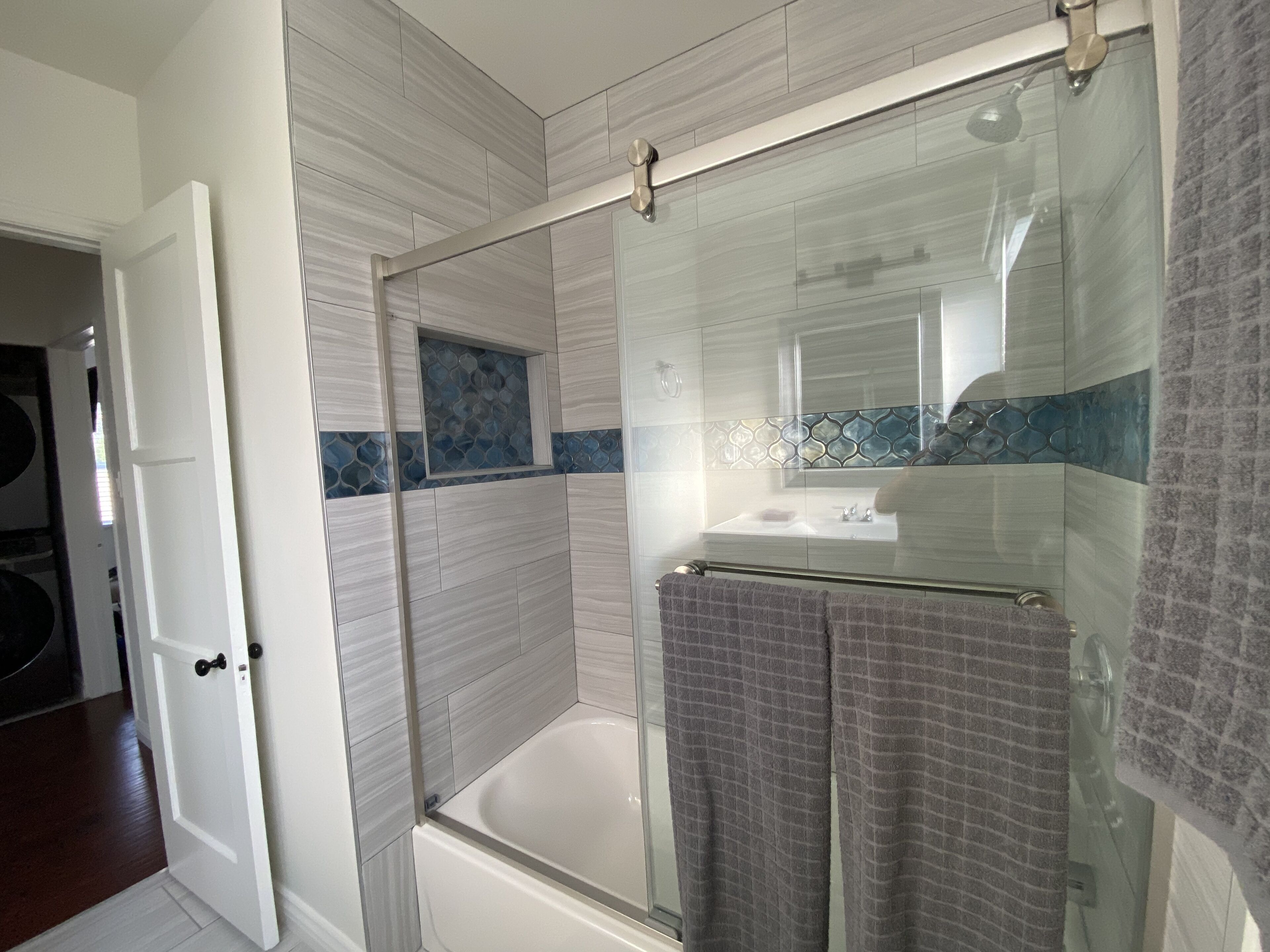 A modern bathroom with a glass shower enclosure, a bathtub, and a vanity with a mirror.