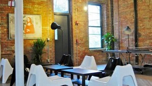 Una habitación con paredes de ladrillo, una mesa de ping pong y sillas blancas.