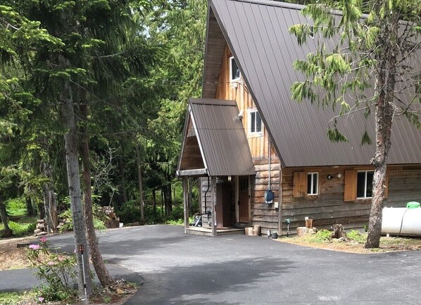 A log cabin with a sloped roof, a porch, and a garage.