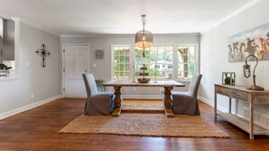 A spacious dining area with a wooden table, two chairs, a woven rug, and a pendant light. - Modern Smyrna Home Near Truist Park (Smyrna)