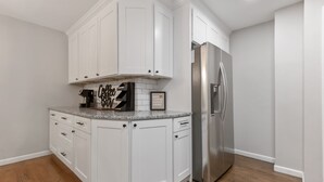 A kitchen with white cabinetry, a stainless steel refrigerator, and a coffee maker on the countertop.