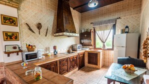 Une cuisine avec un mur recouvert de carreaux, des meubles en bois, un îlot central et un coin repas comprenant une table et des chaises.