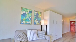 Un salon avec un canapé, deux coussins, une lampe et une armoire.