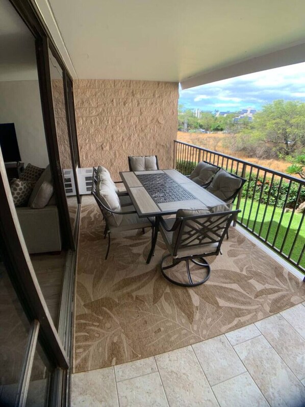 Un balcón con mesa y sillas, un sofá, y vistas del paisaje.