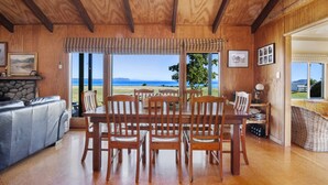 A wooden interior with a dining table and chairs, a sofa, and a fireplace.