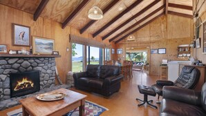 A spacious living room with a stone fireplace, leather sofas, and a dining area with a view of the outdoors.
