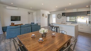Une cuisine moderne avec un îlot central, un coin repas doté d’une table en bois et un salon avec un canapé bleu.