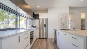 Une cuisine moderne avec des meubles blancs, des appareils en acier inoxydable et une grande fenêtre donnant sur un paysage magnifique.