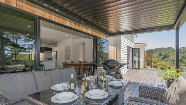 Un espace de restauration en plein air avec une table dressée pour quatre personnes, entouré de meubles en osier, et offrant une vue sur un paysage luxuriant.