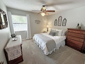 Un dormitorio con cama, cómoda, mesita de noche, lámpara y decoración mural.